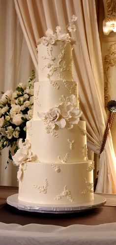 a wedding cake sitting on top of a table next to a vase with white flowers