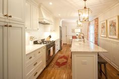 a kitchen with white cabinets and an island in the middle is lit by pendant lights