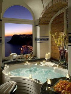 an indoor jacuzzi tub with candles on the side and water in the background