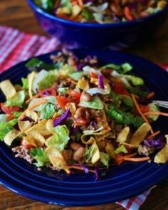 two blue plates filled with salad on top of a wooden table