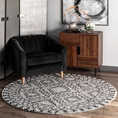 a black and white rug in a living room next to a wooden cabinet with a painting on the wall