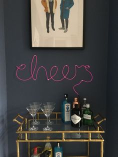 a bar cart with drinks and liquor bottles on it in front of a framed photograph