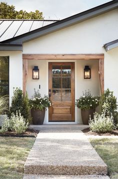 a white house with potted plants on the front door and steps leading up to it