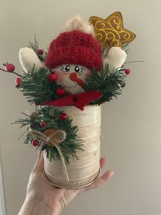 a hand holding a small christmas decoration in a jar