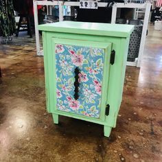 a green cabinet with flowers painted on it in a store floor next to other items