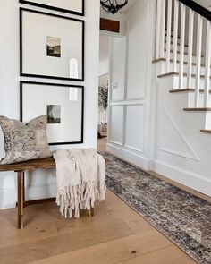 there is a bench and some pictures on the wall in this living room with wood flooring