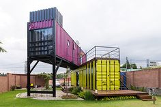 a house made out of shipping containers in the grass with stairs leading up to it