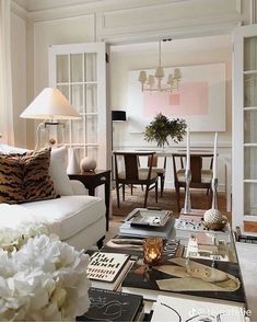 a living room filled with white furniture and lots of flowers on top of the coffee table