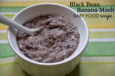 a white bowl filled with black bean baby food mash on top of a green and yellow table cloth