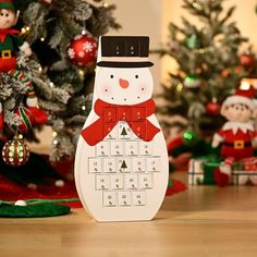 a snowman is sitting in front of a christmas tree with other ornaments and decorations