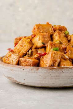 a white bowl filled with tofu and vegetables