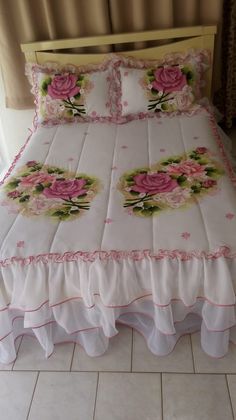 a bed with pink roses on it in a room next to a curtain and window