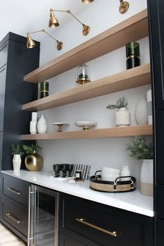 a kitchen with black cabinets and white counter tops, gold accents on the upper shelves