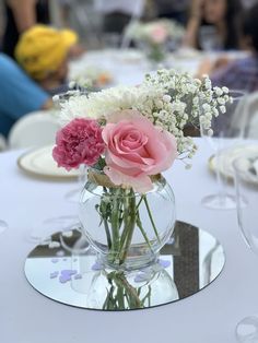 a vase filled with pink and white flowers on top of a table next to plates