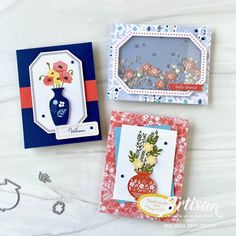 three cards with flowers on them sitting next to some scissors and other crafting supplies