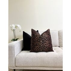 a leopard print pillow sitting on top of a couch next to a vase with flowers