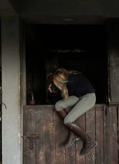 a woman leaning on the side of a wooden door