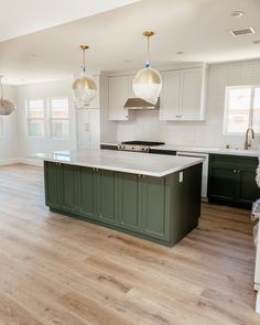 a large kitchen with an island in the middle and two pendant lights hanging from the ceiling