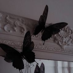 two black butterflies sitting on top of a white mantle next to a chandelier