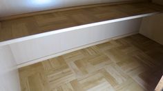 an empty room with wood flooring and white walls, looking down at the corner