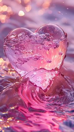 a pink heart shaped object floating in water with bubbles on the surface and light shining behind it