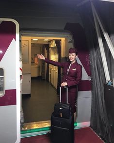 a woman in an airplane cabin with her luggage and waving to the side while standing on the door way