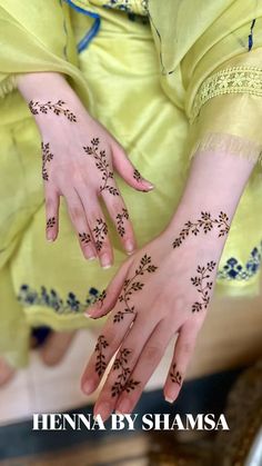 a woman's hands with hennap on her left hand and fingers, both decorated with flowers