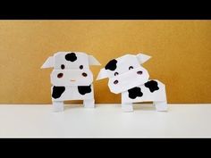 two paper cows are standing next to each other