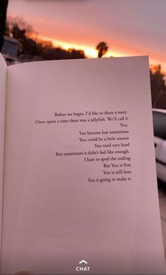 an open book with a poem written on it in front of a sunset and parked cars