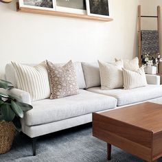 a living room with white couches and pictures on the wall above them, along with a wooden coffee table