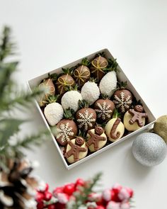 a box filled with chocolate covered cookies next to a christmas ornament and pine cones