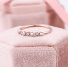 three stone ring sitting on top of a pink velvet cushion in front of a box