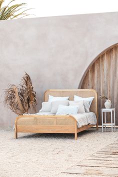 a bed sitting in front of a wall next to a plant