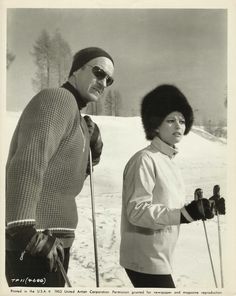 an old black and white photo of two people on skis