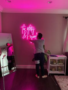 a person standing in front of a pink neon sign