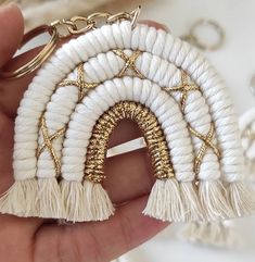 a hand holding a white and gold keychain with tassels on it