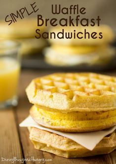 a stack of waffle sandwiches sitting on top of a wooden table next to a glass of orange juice