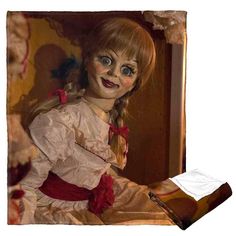 a creepy doll sitting on top of a bed next to a pillow with the image of a woman's face