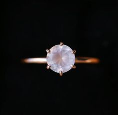 an engagement ring with a white diamond in the center on a black background, close up