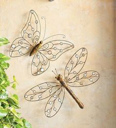 two metal dragon sculptures sitting on top of a wall next to a plant and clock