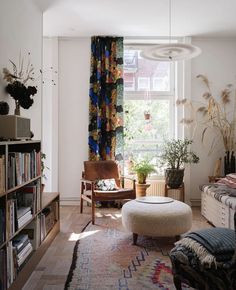 a living room filled with furniture and a large window covered in colorful curtained drapes