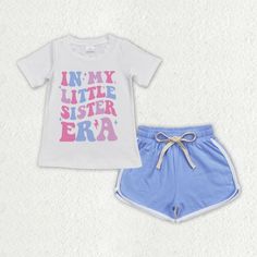 a white shirt and blue shorts with pink letters on it are sitting next to each other