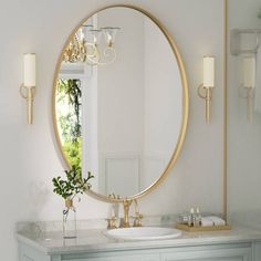 a bathroom with a large round mirror and gold fixtures on the wall above the sink