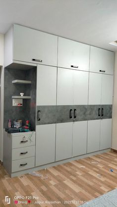 an empty room with white cabinets and wood floors