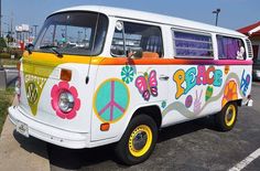 an old vw bus painted with flowers and peace signs is parked in a parking lot