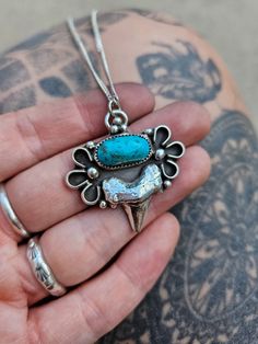 REAL Sand Casted Shark Tooth with oval cut Kingman Turquoise set in a serrated bezel. She is accented with half round wire around both sides resembling flowers and hangs on a super flat Stirling Silver high polished 20 inch Curb chain. Shark Tooth is .999 Fine Silver Sand casting involves the use of a furnace, metal, pattern, and sand mold. The metal is melted in the furnace then poured into the cavity of the sand mold, which is formed by the pattern. The molten material then cools until it solidifies into the desired shape. Handmade - buying handmade jewelry means you'll have an absolutely one of a kind craftsman piece! .925 Curb Chain 20 Inch Long Silver has been oxidized to show off contrast, depth, and to highlight the details then hand polished to a high shine. Every Sol Metallum piec Southwestern Style Hand Forged Turquoise Jewelry, Vintage Hand Forged Oval Jewelry, Hand Forged Vintage Oval Jewelry, Southwestern Hand Forged Turquoise Jewelry, Oxidized Turquoise Oval Jewelry, Vintage Turquoise Jewelry With Oxidized Finish, Vintage Turquoise Oval Pendant Jewelry, Adjustable Turquoise Flower Pendant Jewelry, Turquoise Shell-shaped Necklace For Gift