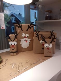 some brown paper bags with reindeer faces and noses on them sitting on a counter top