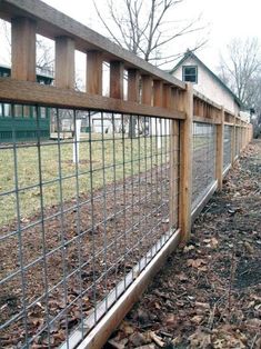 the fence is made of metal wire and wood, along with leaves on the ground