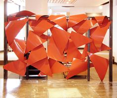 an orange sculpture sitting on top of a tiled floor next to a wall filled with mirrors