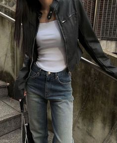 a woman wearing jeans and a leather jacket